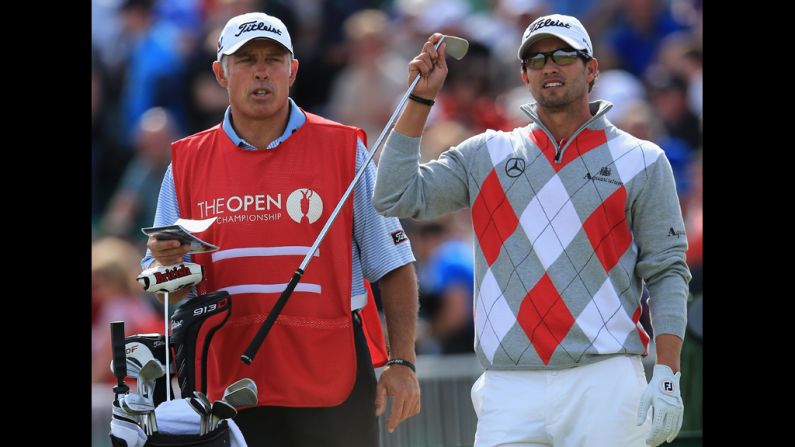 Scott pulls a club as caddie Steve Williams looks on.