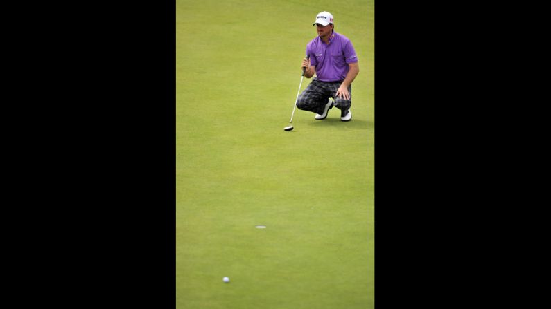 McDowell squats to line up a putt on the second green.