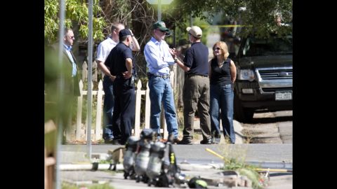 Law enforcement officers speak with Colorado Gov. John Hickenlooper, center, outside the suspect's apartment July 21, 2012.