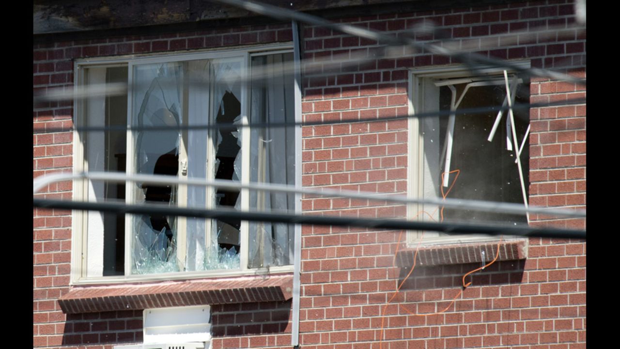 Debris flies out a window, right, after law enforcement officers detonate an explosive device inside the apartment July 21, 2012.