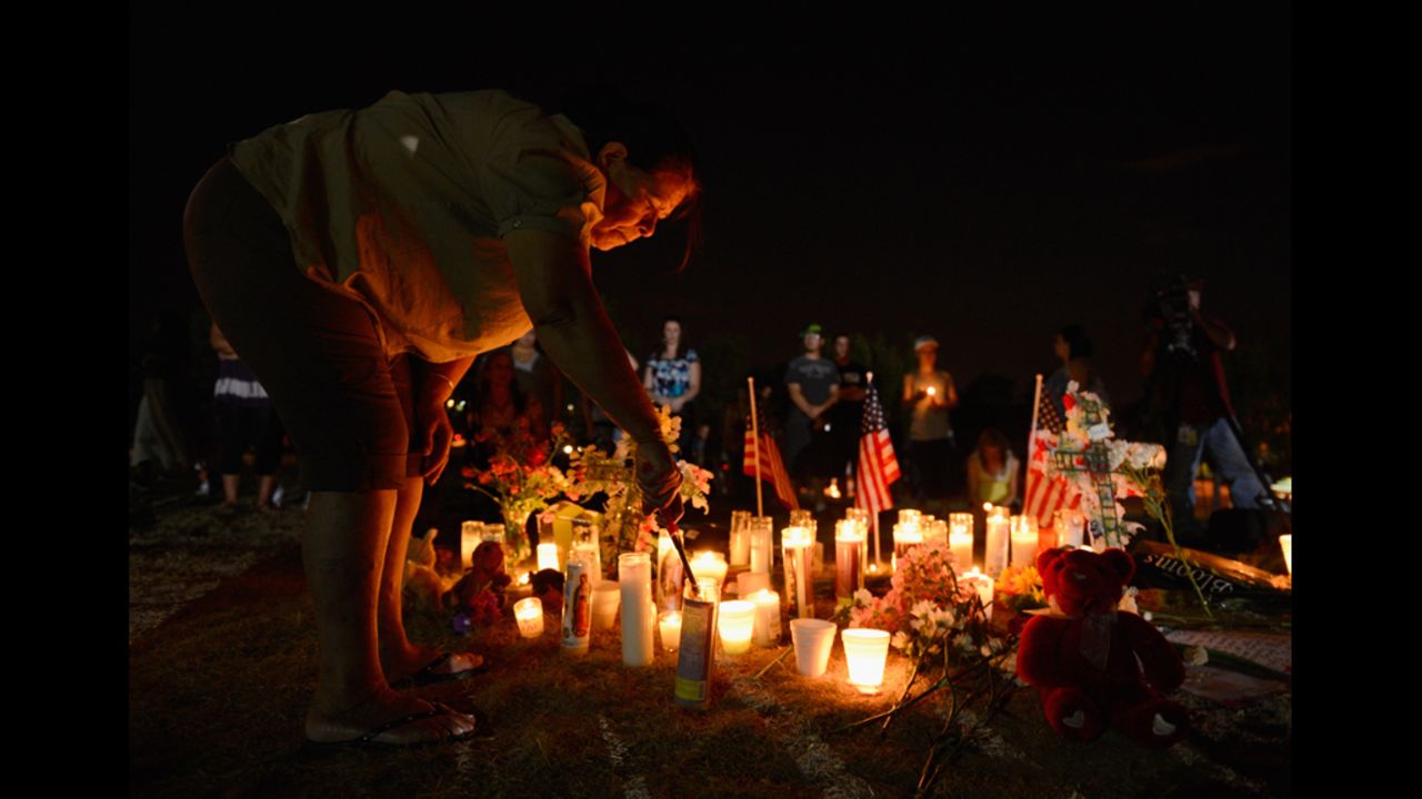 A woman lights a candle at a makeshift memorial where the victims of the massacre are mourned.