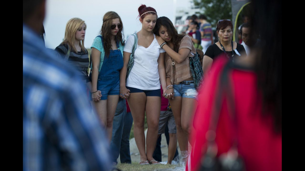 Mourners hold hands at a vigil near the theater.