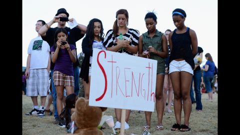 A group of teenagers stand behind a sign that reads "Strength." 