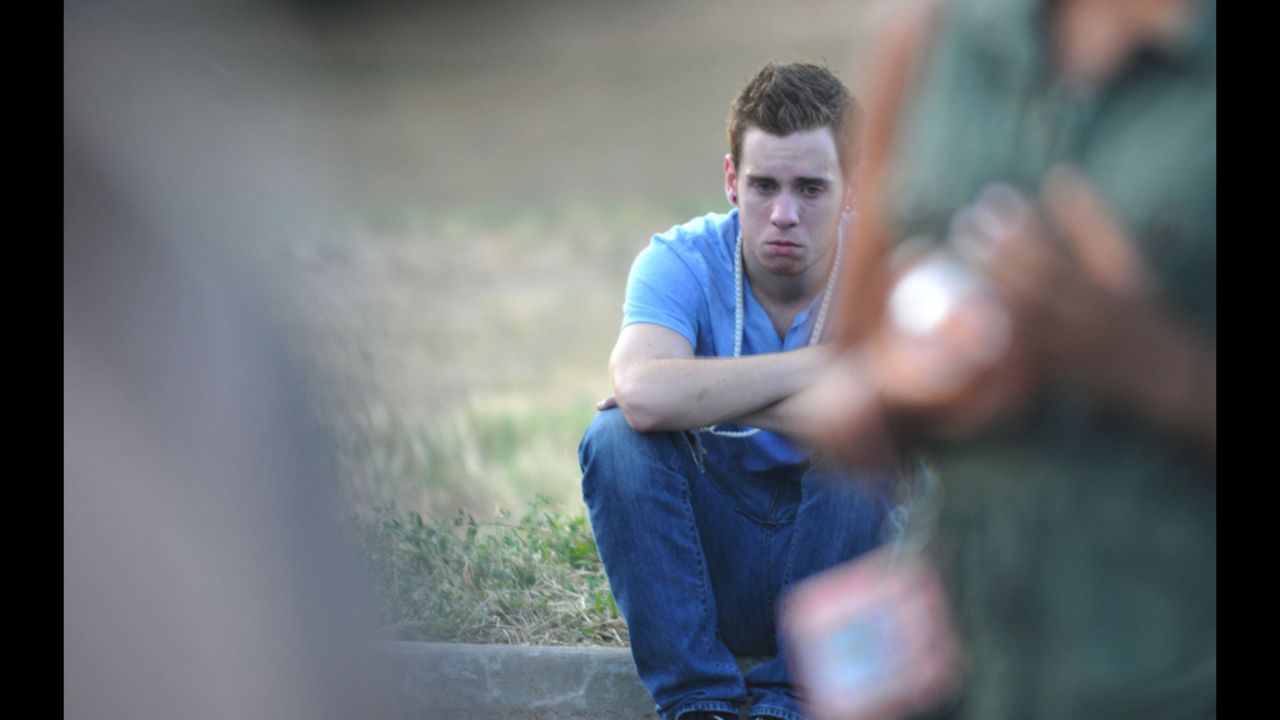 A mourner grieves on the curb during a memorial service.
