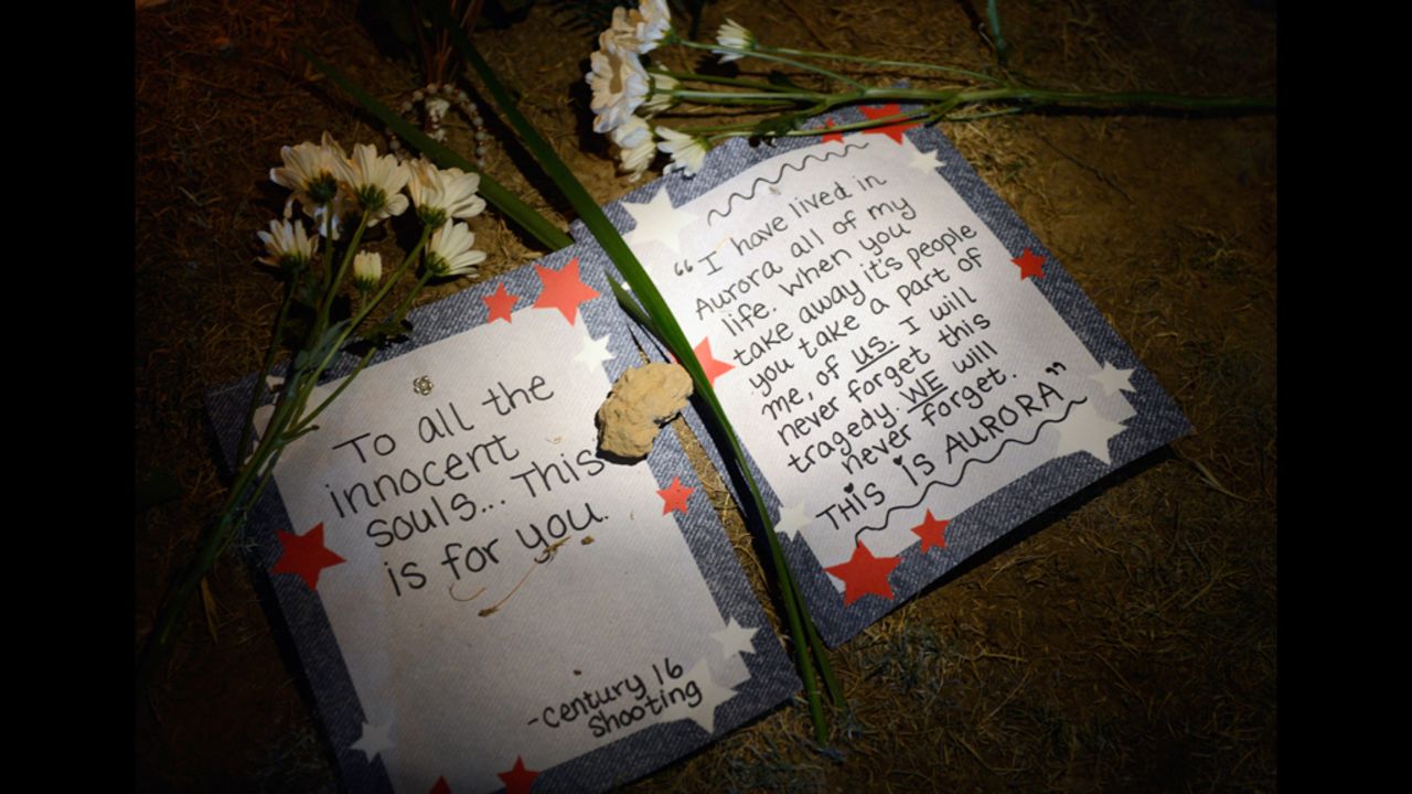 Handwritten consolation letters lie beneath flowers at a makeshift memorial.