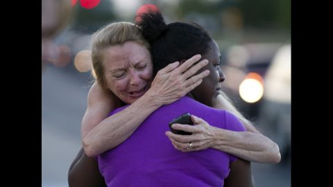 Two women mourn near the theater on Saturday.