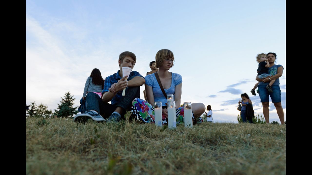 Nathan Mendoza, left, and Melissa Clark sit on the grass during a vigil.