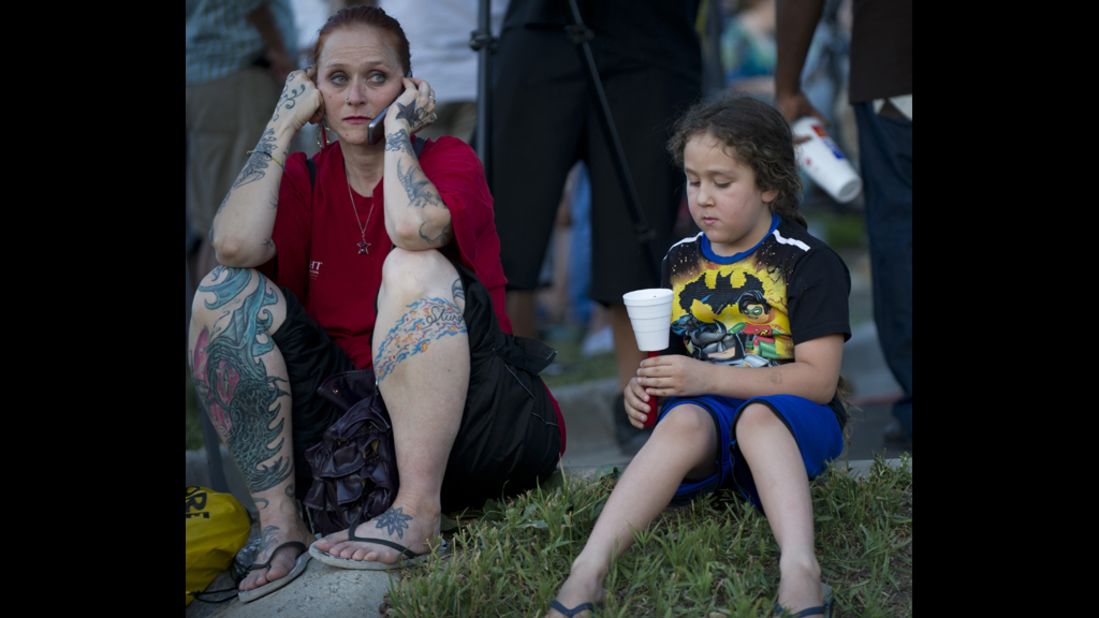 Two mourners sit on the ground at a vigil. 
