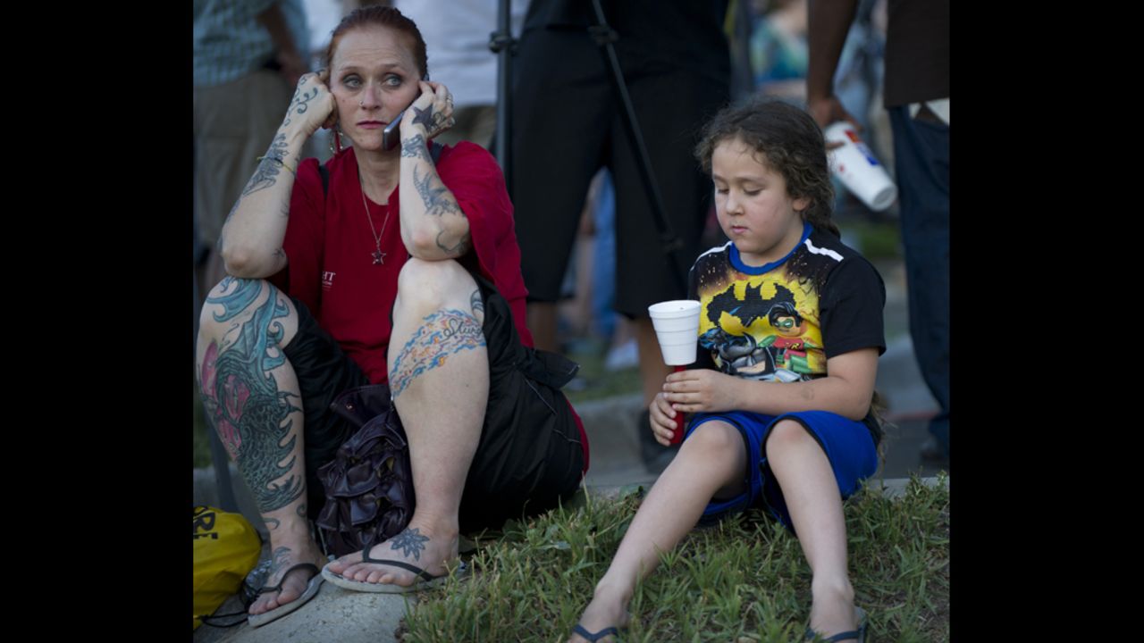 Two mourners sit on the ground at a vigil.