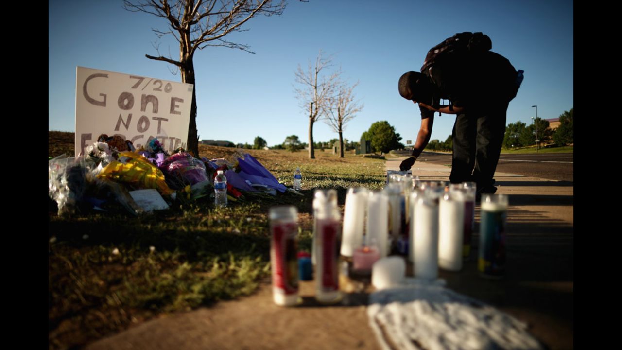 Gerald Wright, 24, relights candles that have blown out at the victims' memorial across from the movie theater.