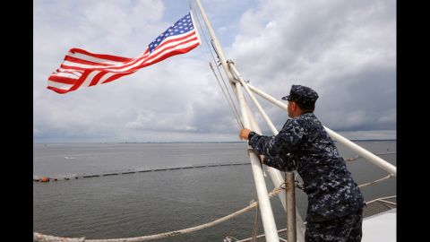 Aviation Boatswain's Mate 3rd Class Jajuan Mangual lowers the American flag on the flight deck of the aircraft carrier USS George H.W. Bush to half-mast on Saturday. One U.S. Navy sailor was killed in the shooting and another injured.