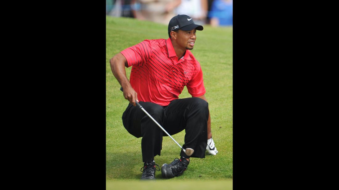 Tiger Woods stumbles and watches the path of his bunker shot on the sixth hole Sunday.