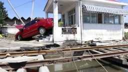 A  flood-swept car is lodged against a building at a railway crossing in Beijing on Saturday. 