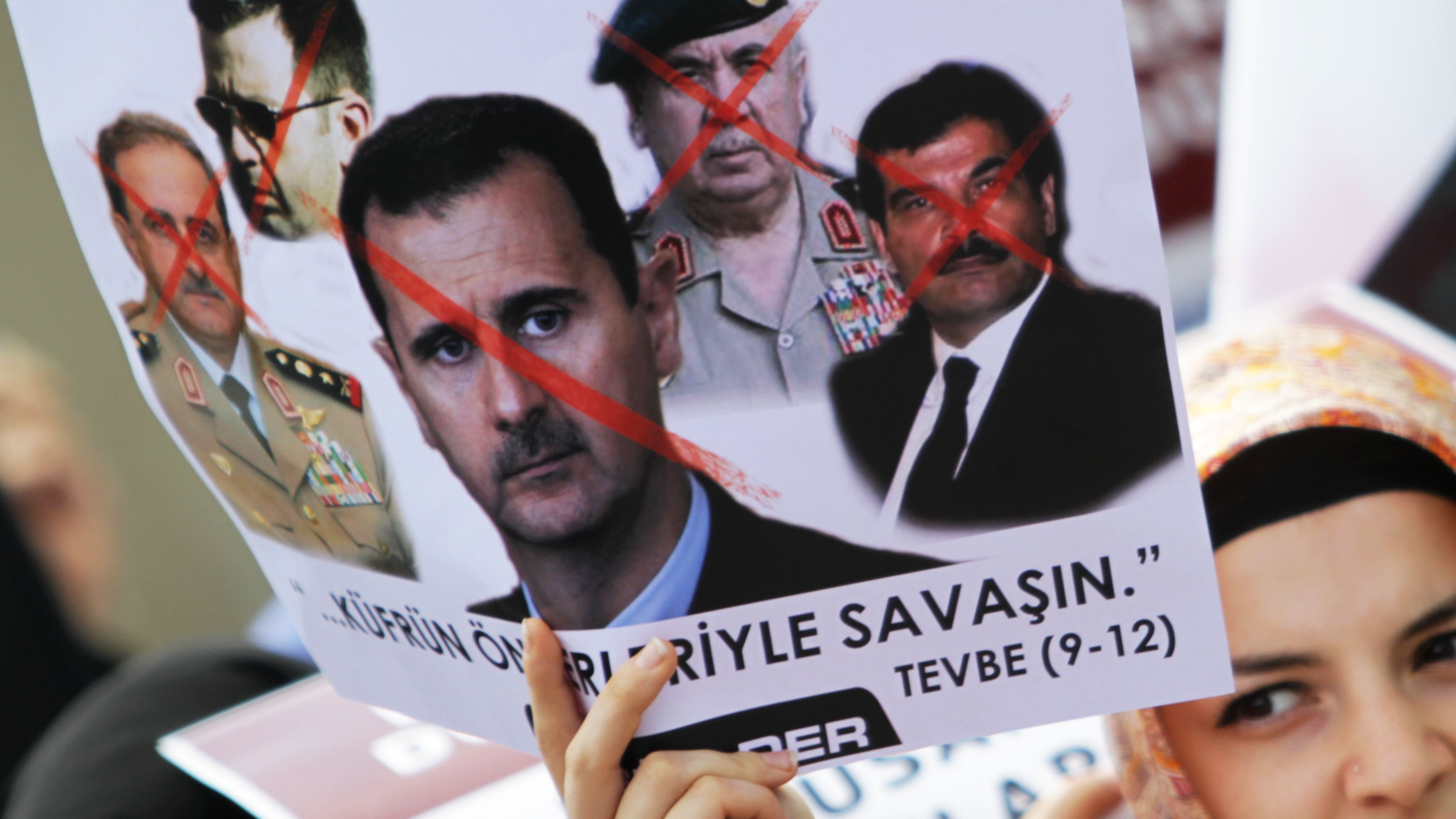 A woman holding a placard protesting against President Bashar al-Assad's regime.