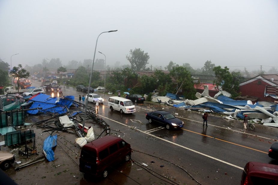 Commuters make their way home through roadside debris as a storm hits Beijing, July 21.