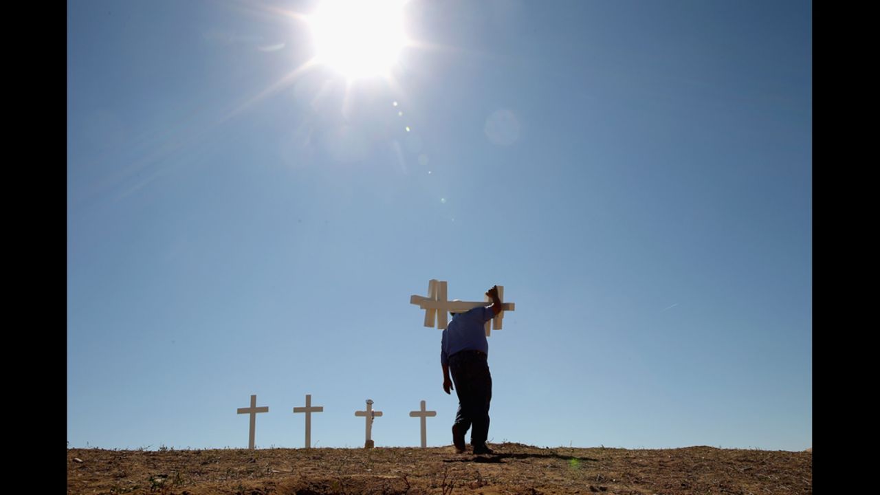 Greg Zanis of Aurora, Illinois, carries two of the 12 crosses he made for a makeshift memorial to the victims of last weekend's mass shooting at the Century 16 movie theater on Sunday, July 22.