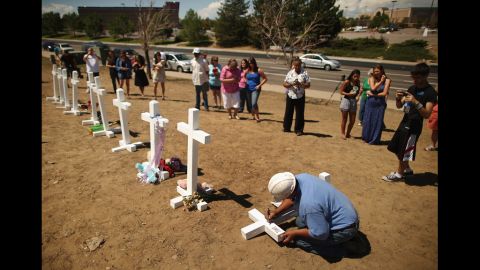 Greg Zanis writes the names of the victims of last weekend's mass shooting on the crosses before erecting them at the memorial across from the Century 16 movie theater on Sunday. Zanis, a carpenter, drove all night from Illinois to deliver the crosses.