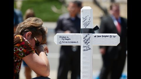 Angie Terry of Alabama prays next to a white wooden cross erected for victims.