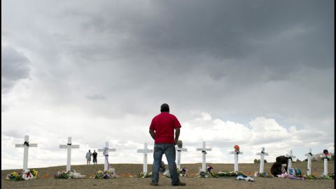 A man pauses before the crosses at the memorial near the Century 16 movie theater on Sunday.