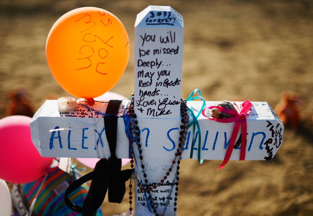 A cross stands at the makeshift memorial for victims across the street from the Century 16 theater on Tuesday.
