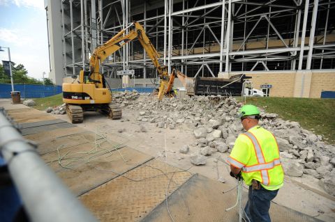 Workers on Tuesday, July 24, remove the concrete landing area and wall where the Joe Paterno statue once stood in State College, Pennsylvania.