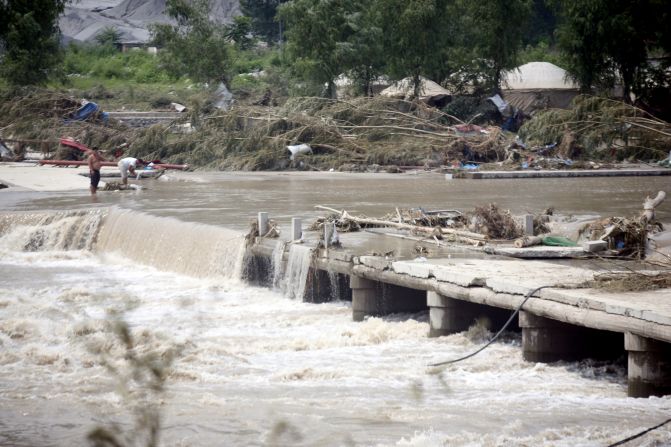 Water pours over a collapsed bridge leading to Laishui on Tuesday.  The heavy rains have affected more than 6 million people in China. 