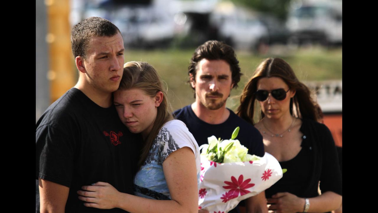 A couple embraces as "Dark Knight Rises" star Christian Bale and his wife, Sandra Blazic, wait to place flowers at the memorial on Tuesday.