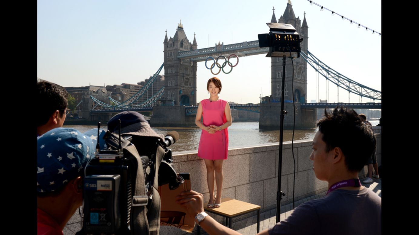A South Korean news crew reports from in front of the Tower Bridge where Olympics Rings hang.