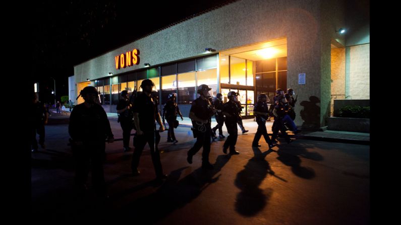 A line of officers moves through a shopping center.