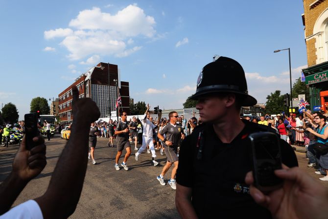 Torchbearer Scott Moorhouse, a Paralympic javelin thrower, runs with the Olympic flame along Tottenham High Road in London on Wednesday, July 25.