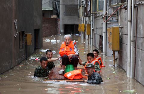 Rescuers evacuate an elderly woman from her flooded home in Chongqing, southwest China, July 23, 2012.