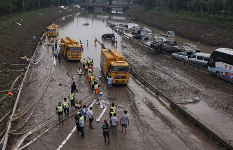 Municipal workers try to clear water on a section of the Beijing-Hong Kong-Macau expressway, where more than 80 cars were submerged on Monday, July 23, in Beijing.
