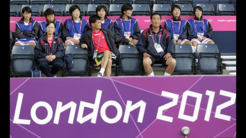 North Korean soccer coach Gun Sin Ui, at center in red shirt, waits for his team's match to begin at Hampden Park in Glasgow, Scotland, on Wednesday, July 25. The first-round match against Colombia was delayed. 