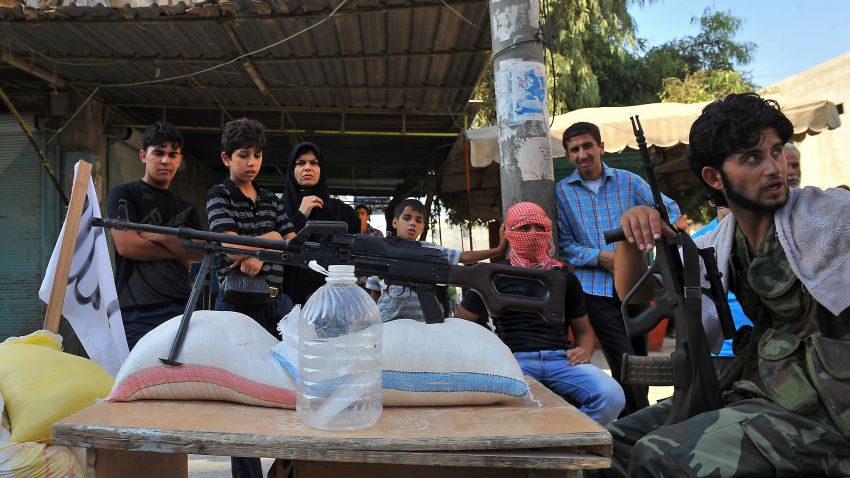 Syrian people stand next to a checkpoint manned by rebels in the northern city of Aleppo on July 24, 2012. 