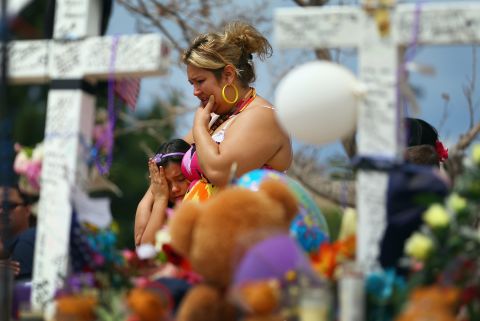Angella Aquilis, left, and Maria Olivas mourn together at a makeshift memorial across the street from the Century 16 movie theater Wedesday, July 25.