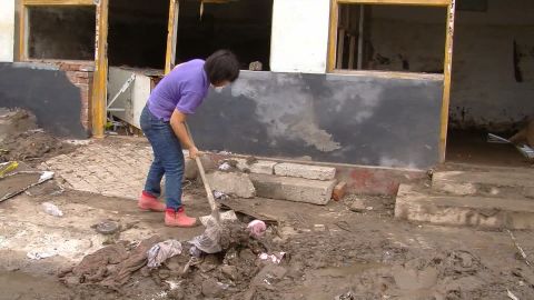 A woman cleans mud from her home in the Fangshan district of Beijing, China, July 25, 2012