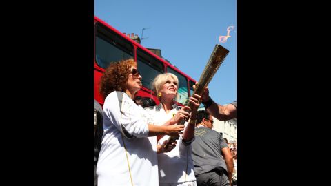 Torchbearers Jennifer Saunders and Joanna Lumley, known for their "Absolutely Fabulous" characters Edina and Patsy, carry the Olympic flame through Lambeth, Kensington and Chelsea on Thursday,  July 26, in London.