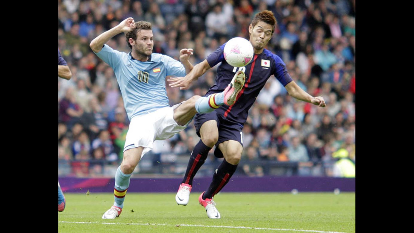 Spain's Juan Mata, left, challenges Hotaru Yamaguchi of Japan during a group D soccer match Thursday in Glasgow.