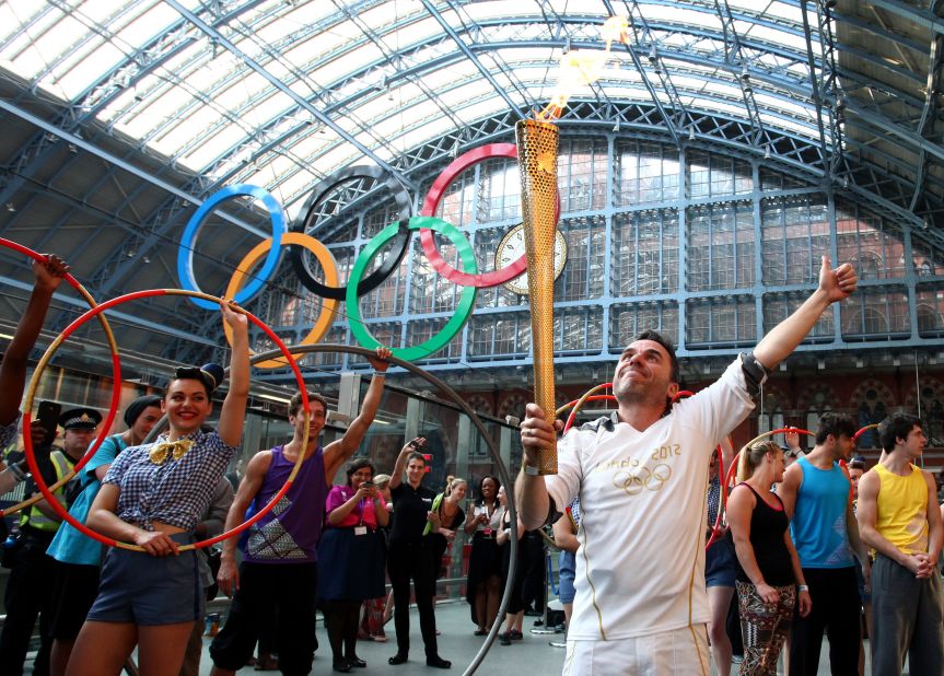 Torchbearer Daniel Mccubbin holds the Olympic flame inside St. Pancras International Railway Station on Thursday, July 26.