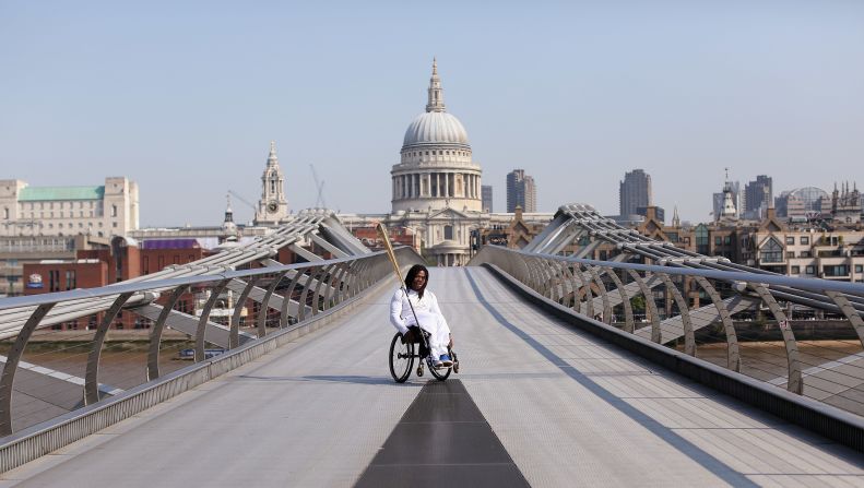 Wheelchair basketball player Adedoyin Adepitan of Great Britain carries the Olympic flame Thursday over Millennium Bridge in front of St. Paul's Cathedral in London.