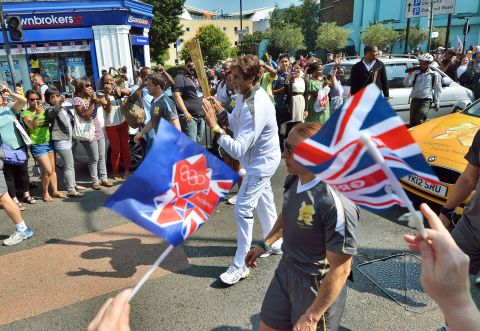 Indian Bollywood actor Amitabh Bachchan, center, carries the Olympic flame through the streets of London on Thursday, July 26, the day before the opening ceremony.