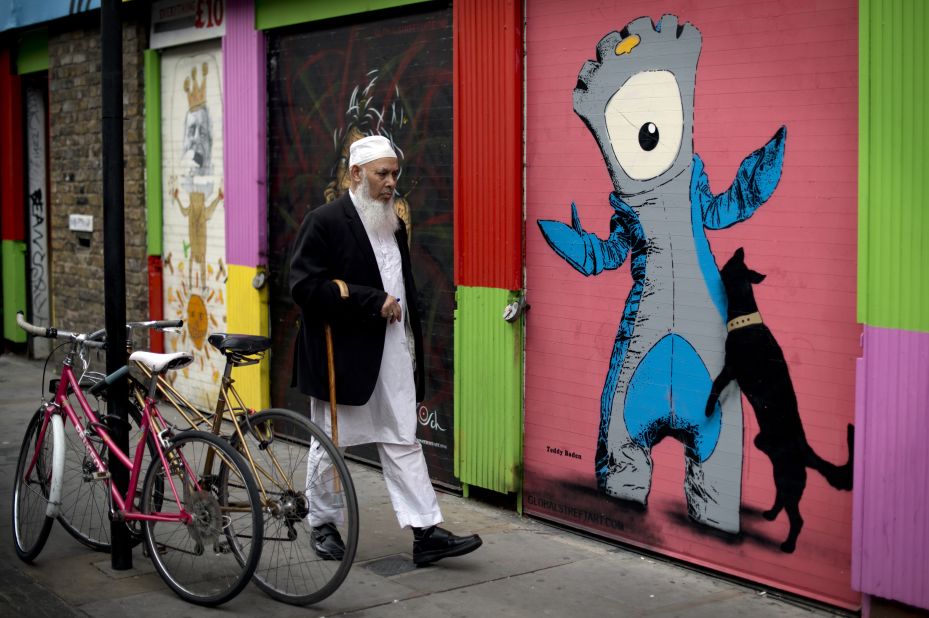 A man walks past graffiti depicting 'Mandeville' (R), one of the official Olympic mascots, in east London two days before the start of the Games.