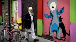 A man walks past graffiti depicting 'Mandeville' (R), one of the official Olympic mascots, in east London two days before the start of the Games.
