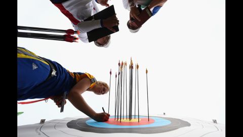 Kaori Kawanaka of Japan, Pia Lionetti of Italy and Tetyana Dorokhova of Ukraine retrieve their arrows Friday during the archery ranking round on opening day of the Olympics in London.