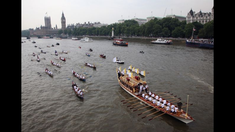 The Queen's royal row barge Gloriana carries the Olympic flame along the River Thames past the Parliament on Friday, July 27, the final day of the torch relay in London.