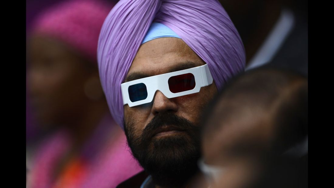 A man wearing glasses waits for the start of the opening ceremony.