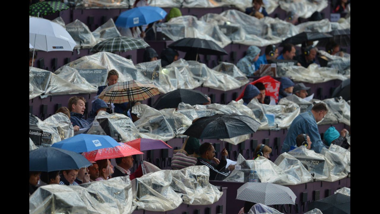 Spectators take shelter under umbrellas prior to the start of the opening ceremony.