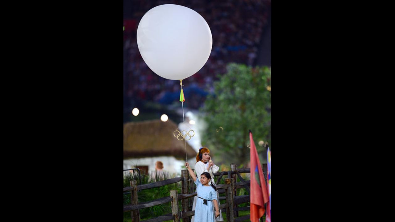 A young performer holds a balloon bearing the Olympic rings.