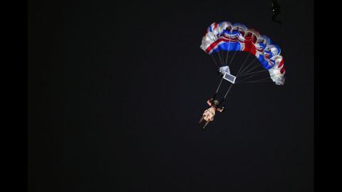 An actor dressed to resemble Britain's Queen Elizabeth II parachutes into the stadium.
