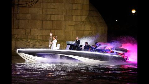 David Beckham passes under Tower Bridge driving a speedboat named "Max Power," which carries the Olympic Torch.